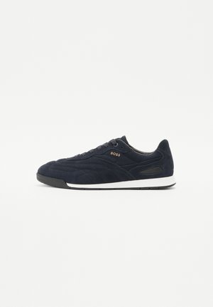 Baskets basses en daim bleu marine avec semelle noire, semelle intermédiaire blanche et logo doré "BOSS" sur le côté, vues de profil.