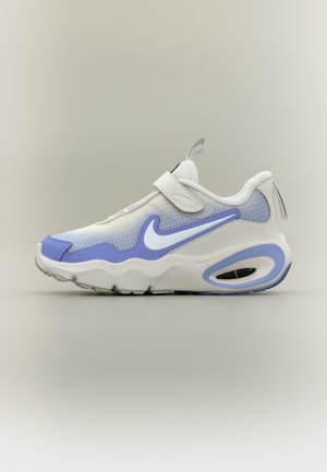 Scarpa da ginnastica Nike bianca e lilla chiaro con cinturino a strappo, tomaia in mesh, suola spessa e ammortizzazione ad aria visibile su uno sfondo neutro.