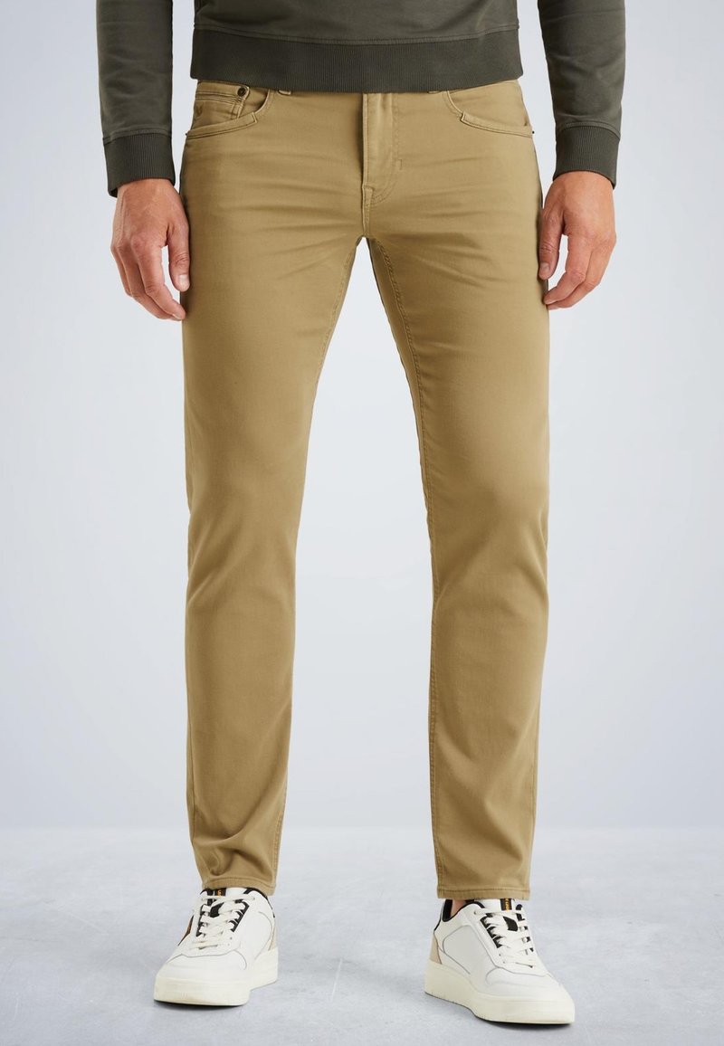 Tan cotton trousers with a slim fit, featuring five pockets, a zipper fly, and contrasting stitching, paired with white sneakers.