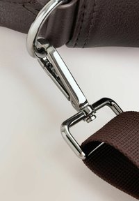 Correa de cuero marrón con un clip de metal cromado, que presenta un acabado texturizado y una sección de tejido resistente en un tono marrón más oscuro.
