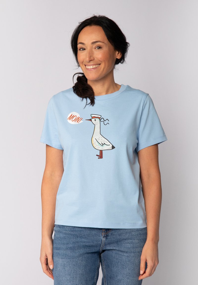 T-shirt bleu clair à manches courtes présentant un graphisme d'un oiseau portant un chapeau de marin avec l'inscription "MONI". Fabriqué en tissu doux et respirant.