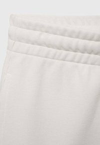 Pantalon de survêtement blanc avec une finition texturée, doté d'une taille élastique avec un design à double couture et des coutures apparentes.