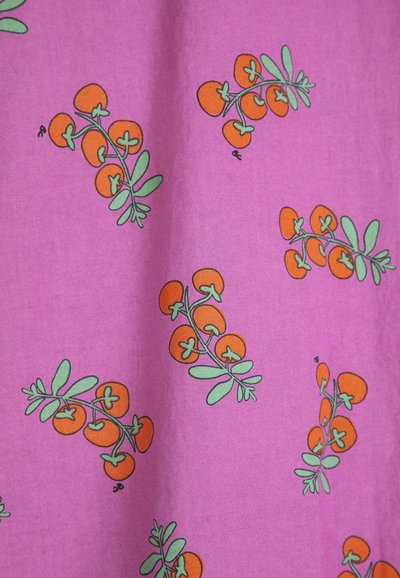Tissu violet avec un motif répétitif de petites tomates cerises orange et de feuilles vertes sur des tiges.