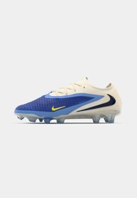 Nike football cleat featuring a blue textured upper with cream accents, yellow logo, and transparent sole with molded studs for traction.