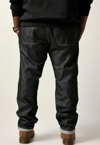 Jeans in denim scuro con una vestibilità comoda e orli risvoltati, dotati di tasche posteriori contornate da cuciture a contrasto.