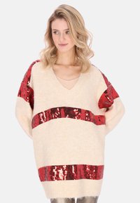 Maglione oversize di colore crema con strisce rosse di paillettes, design con scollo a V e tessuto morbido. Vestibilità ampia con maniche larghe.