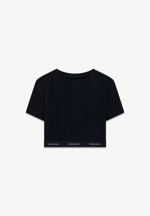 Schwarzes cropped T-Shirt aus weichem Stoff mit kurzen Ärmeln und rundem Halsausschnitt. Mit einem gebrandeten Band am Saum, auf dem "GUESS JEANS" in Weiß steht.