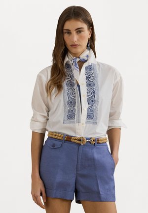Camisa branca com padrões azuis bordados na parte da frente, combinada com calções azuis claros e um cinto de corda bege, apresentando um fecho de botão frontal.