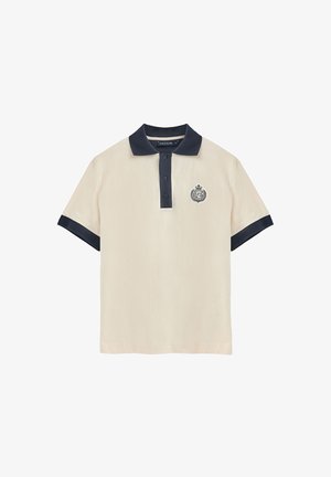 Koszulka polo w kolorze kremowym z granatowym kołnierzykiem i rękawami. Posiada zapięcie na trzy guziki oraz haftowane logo po lewej stronie klatki piersiowej. Gładka tekstura materiału.
