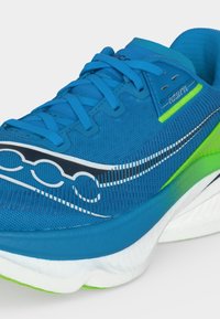 Μπλε αθλητικό παπούτσι Saucony Endorphin Izumi με λευκή και πράσινη σόλα, πλέγμα στο επάνω μέρος και κλείσιμο με κορδόνια, στο δεξί πλάγιο.