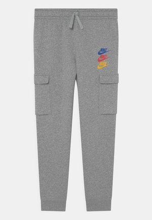 Pantalon de survêtement gris avec taille à cordon, poches cargo latérales et logos Nike bleus, rouges et jaunes sur la partie supérieure de la cuisse gauche.