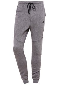Grå Nike-sweatpants med dragsko i midjan, avsmalnande ben och texturerat tyg med sidopanelaccenter och en liten logotyp nära höften.