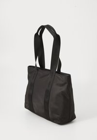 Sac fourre-tout noir en tissu doux, doté de deux solides sangles noires embossées et d'un design spacieux avec un zip sur le dessus.