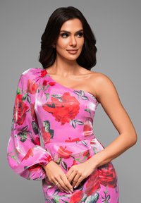 Robe décolletée faite d'un tissu rose vif avec des motifs floraux rouges. Avec des manches bouffantes et une silhouette ajustée, elle présente une texture lisse.