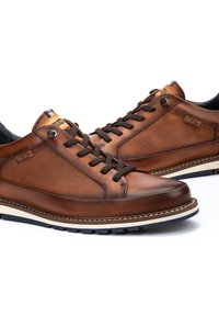 Zapatillas de cuero marr�ón con acentos de textil, con cordones redondos, suela en contraste y un pequeño logotipo en el lateral. Textura suave.