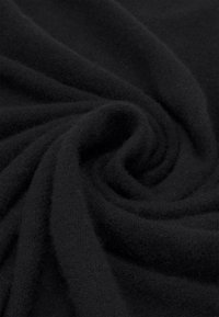Tissu noir doux plié en un motif tourbillonnant montrant sa texture et son épaisseur.