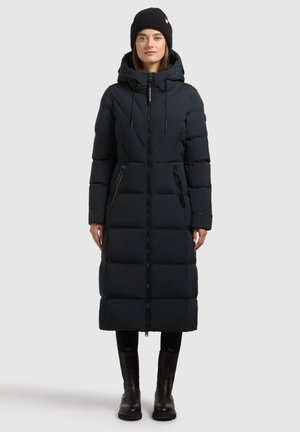 Abrigo acolchado largo negro con capucha, cierre frontal y dos bolsillos con cremallera. Presenta un diseño acolchado cuadrado y una longitud hasta la pantorrilla. Gorro negro usado.