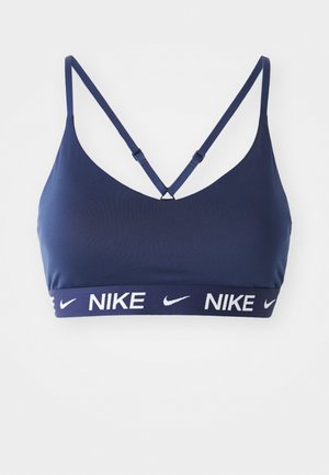 Granatowy stanik sportowy z regulowanymi ramiączkami, dekoltem w kształcie litery V oraz szerokim elastycznym pasem z białym logo Nike. Gładka tekstura materiału.