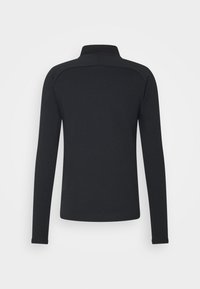 Musta pitkähihainen pikeepaita, jossa korkea kaulus ja istuva malli. Pehmeä, sileä kangas, jossa hienovaraiset saumalistat olkapäiden kohdalla.