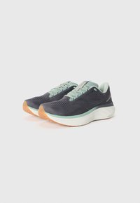 Chaussures de course avec une tige en maille bleu marine, des accents vert foncé discrets et une semelle intermédiaire blanche. Présente une semelle extérieure en caoutchouc texturé pour une meilleure traction.