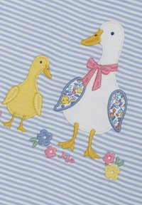 Broderad design av en gul gåsunge och en vit gås med en rosa rosett. Har blå blommiga accenter på vingarna mot en randig blå bakgrund.