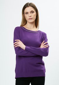 Lila Pullover mit Boat-Ausschnitt, verziert mit einer dekorativen Reihe aus klaren Perlen entlang des Ausschnitts. Weicher Stoff und gerippte Manschetten.