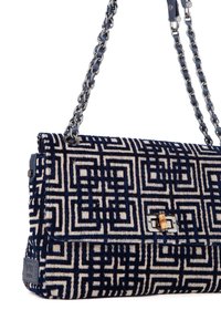 Bolso de mano con patrón en azul marino y crema, superficie texturizada, asa de cadena plateada y detalle de cierre con candado dorado.