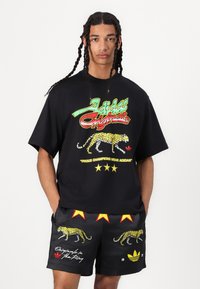Black cotton t-shirt with colorful leopard print and text design. Paired with black shorts featuring star accents and leopard graphics.