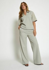 Two-piece outfit with a striped pattern in black and white, featuring a short-sleeve collared top and wide-leg pants. Smooth texture.