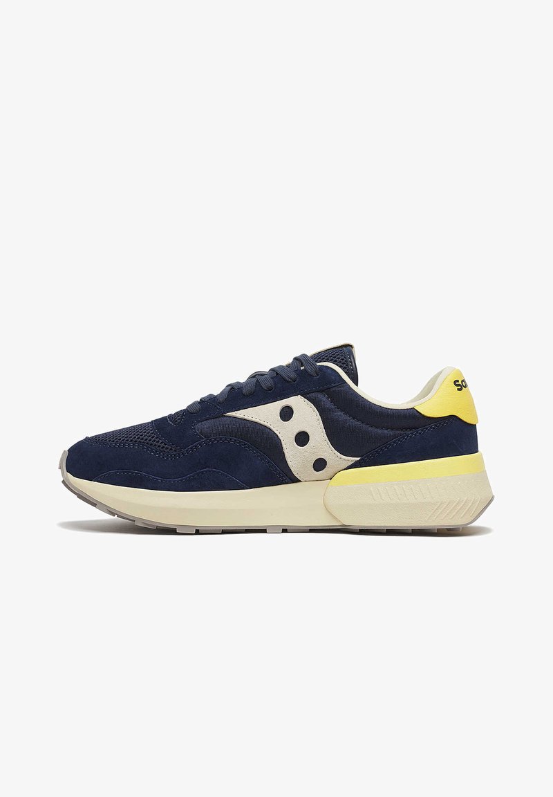 Sneakers blu navy realizzati in suede e mesh, con una sezione centrale crema, un accento giallo sul tallone e una suola in gomma bianca texturizzata.