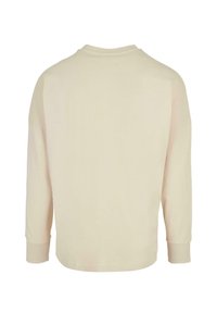 Lys beige langærmet skjorte med rund halsudskæring, blød tekstur og ribbede manchetter. Enkel design uden synlige mønstre eller hardware.