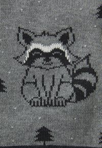Grau gestrickter Stoff mit einem Waschbärenmotiv in Schwarz und Weiß, ergänzt durch Baum-Muster, die eine strukturierte Oberfläche zeigen.