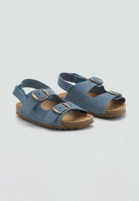 Sandali blu scamosciati con due fibbie regolabili, punta aperta e cinturino per il tallone. Suola in gomma marrone testurizzata per aderenza e comfort.