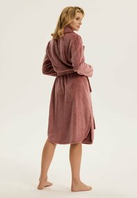 Różowy, teksturowany szlafrok z diamentowym wzorem, długimi rękawami i paskiem w talii. Materiał wydaje się miękki, posiada kołnierz i długość do połowy łydki.