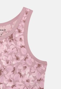 Light pink sleeveless top with a floral pattern in darker pink and brown. Soft fabric and rounded neckline with stitched edges.