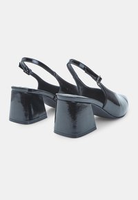 Black patent leather slingback heels with square toes and chunky block heels. Adjustable buckle closure and smooth, glossy texture.