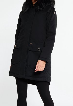 Parka negra aislante con cuello de pelo sintético, cierre delantero de botones y cremallera, dos grandes bolsillos, tejido texturizado y puños ajustables.