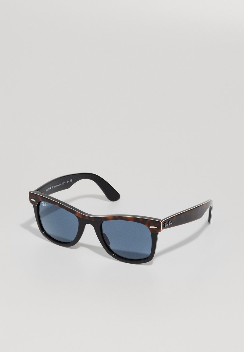 Ray-Ban Wayfarer sunčane naočale s koraljnim okvirom i plavim lećama odlažu se na svijetlu površinu.