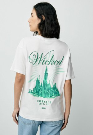 Vit t-shirt med ett grönt grafiskt tryck av Emerald City, texten "Wicked" ovanför och "Emerald City, OZ" nedanför, med en avslappnad passform.