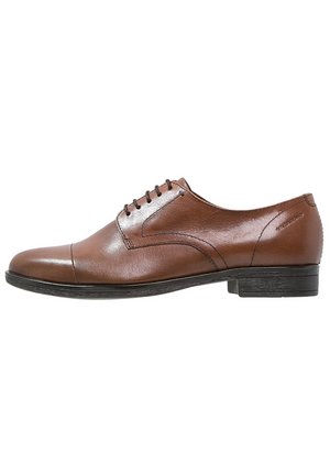 Brauner Herrenschuh aus Leder mit Schnürverschluss, abgestepptem Kappzehenbereich und niedrigem schwarzem Absatz, seitlich auf weißem Hintergrund dargestellt.
