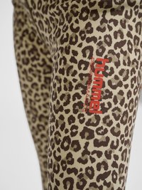 Tissu de legging avec imprimé léopard marron et logo rouge « hummel performance » sur la cuisse.