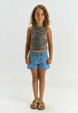 Haut sans manches à imprimé léopard, short en denim avec clous métalliques, et sandales beige. Le short est cintré avec une fermeture par bouton et des poches.