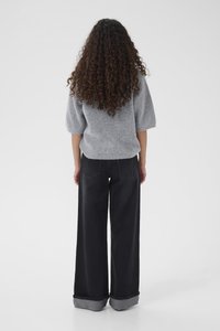 Maglione grigio lavorato a maglia con maniche corte abbinato a jeans neri in denim a vita alta, a gamba larga, con orli risvoltati e tasche posteriori.