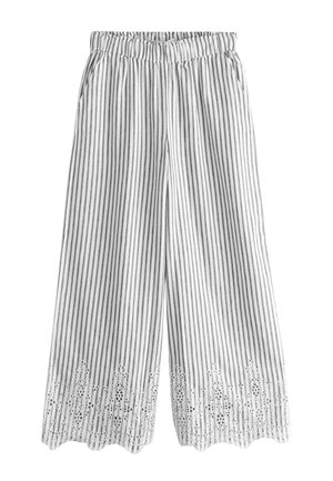 Pantalon blanc à jambes larges avec des rayures noires verticales, taille élastique, poches latérales et broderie en dentelle décorative le long de l’ourlet festonné.