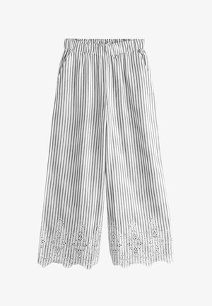 Pantalon blanc à jambes larges avec des rayures noires verticales, taille élastique, poches latérales et broderie en dentelle décorative le long de l’ourlet festonné.