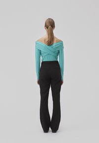 Aqua spalvos off-shoulder viršus su ilgomis rankovėmis, turintis drapiruotą dizainą. Poruojamas su juodomis plačiomis kelnėmis. Lygi tekstūra, prigludusi siluetas.