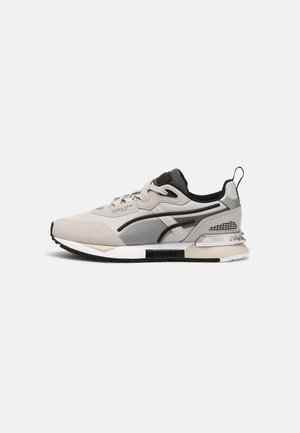 Baskets de sport gris clair et noir avec maillage et superpositions synthétiques, semelle rembourrée et languette au talon, montrées de côté extérieur.