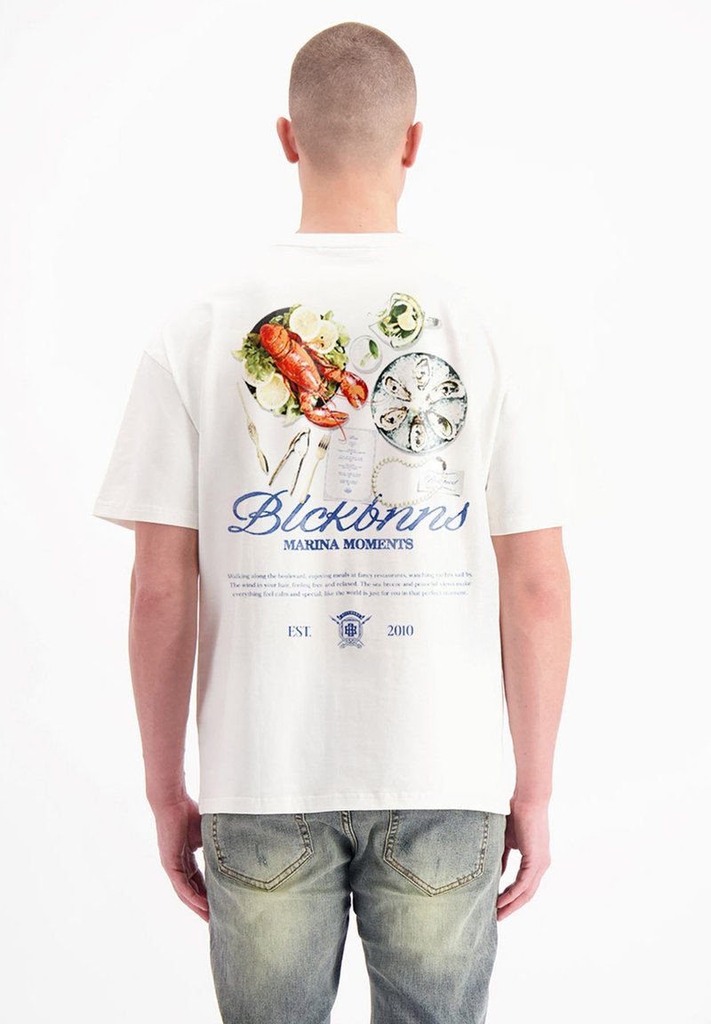 Witte katoenen T-shirt met een afbeelding van zeevruchten op een bord met citroen, vergezeld van blauwe tekst en een logo op de achterkant.