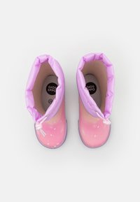 Bottes en caoutchouc roses avec une finition brillante, des poignets en tissu violet et des pois blancs. Conçues pour les enfants, avec un système de fermeture ajustable.
