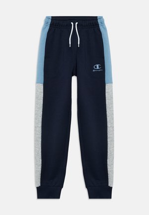 Tmavomodré tepláky so svetlomodrými a sivými bočnými panelmi, elastickým pásom s bielou šnúrkou, manžetami na členkoch a logom Champion na ľavom stehne.